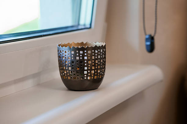 Bronze Perforated Metal Candle Holder on Window Sill, Warm Interior Lighting, Decorative Accents, Moody Atmospheric Scene