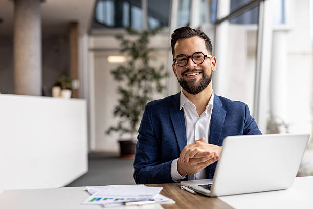istock Smiling businessman working on laptop in modern office 2222887576