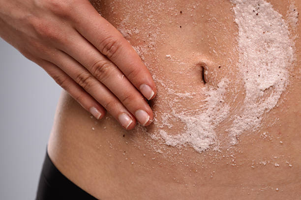 Close-up of a hand applying an exfoliating scrub to skin, improving smoothness and texture. Promotes healthy, glowing skin by removing dead cells and impurities.