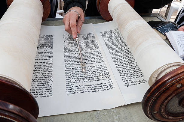 istock Closeup of bar mitzvah boy reading the Torah and using a yad or pointer to guide him through the Hebrew text. 2222892282
