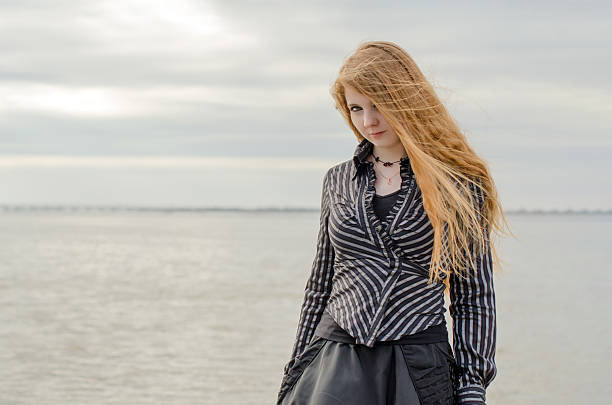 istock Young woman with long hair strolling by tranquil seaside 2222892887