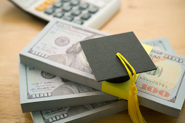 istock Graduation cap university or college degree on stack US dollar banknotes. 2222893753