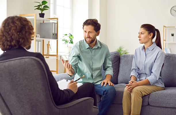istock Young couple sitting on sofa and talking with psychologist on therapy session. 2222895764