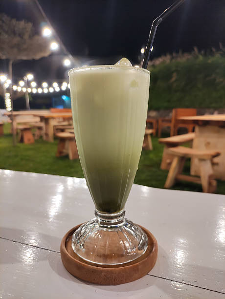 Creamy Matcha Iced Latte Served on Wooden Coaster at Outdoor Cafe