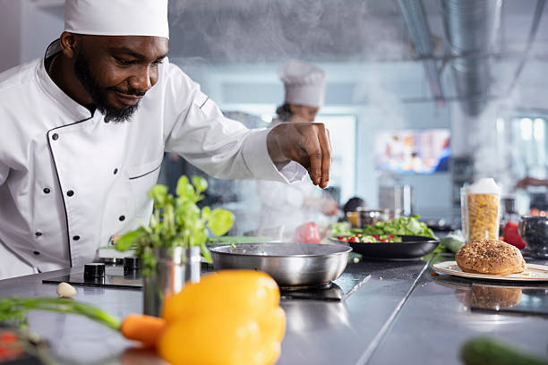 istock African american male chef sprinkles fresh basil over a plated dish 2222899828
