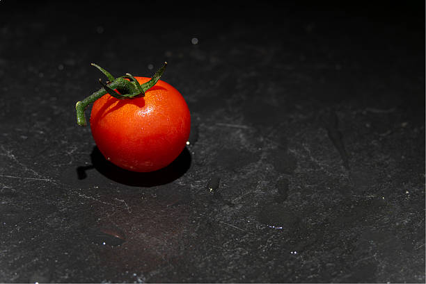 Single Tomato on Black Stone.
