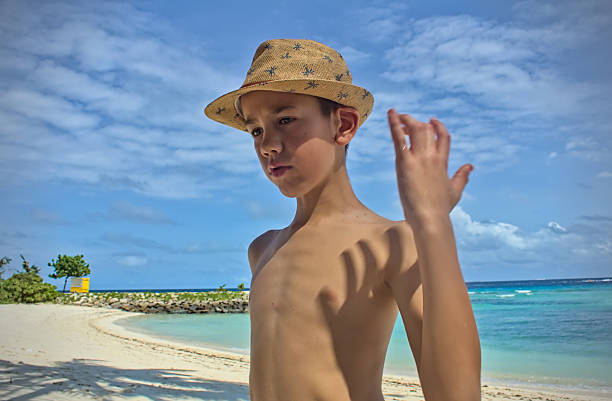 Young boy with hat on a sunny sandy beach close up view, Maldives