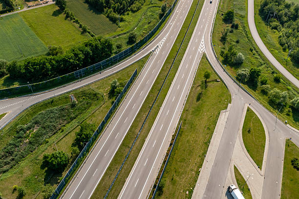 istock Top down view of empty multilane expressway and exit ramp surrounded by summer greenery, road design and infrastructure concept 2222902130