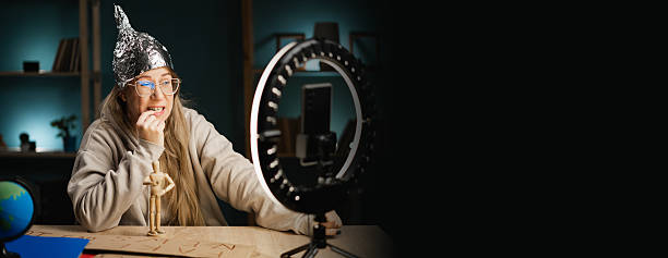 istock Crazy conspiracy theorist blogger streaming live at home using smartphone and ring light, nervous, worried and scared woman in fear and bitting nails. banner. 2222902868