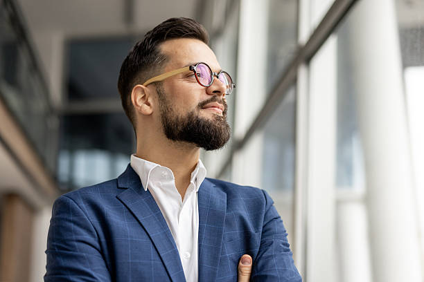 istock Confident businessman looking out large window in modern office building 2222903101