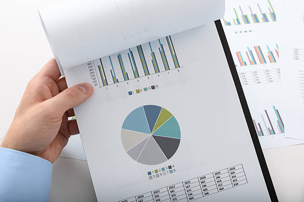 istock A man holds documents, bar charts and pie charts in his hand for financial analysis. 2222904211