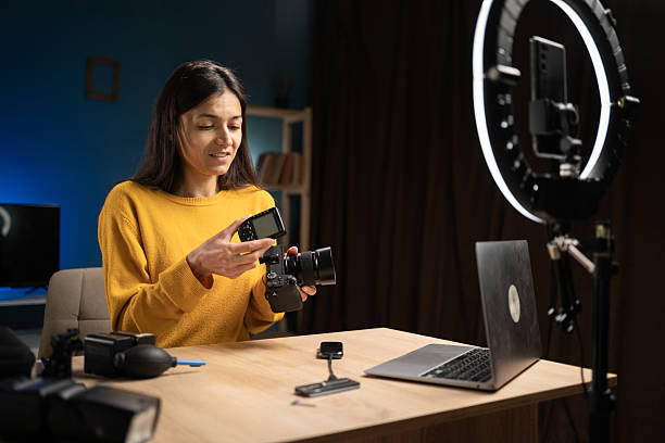 istock photographer content creator using smartphone for social media, vlogging and livestreaming. Influencer photographer hosting educational podcast showing camera with flash trigger 2222904221