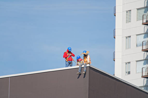 Bangkok, Thailand - November 6, 2007: Thai workers on a building roof, roofer contractors team on wooden frame of a rooftop.