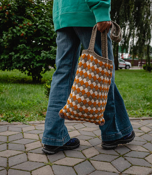 istock A woman walks with a crocheted bag. Tricolor pattern entrelak bound by Tunisian knitting. 2222910568