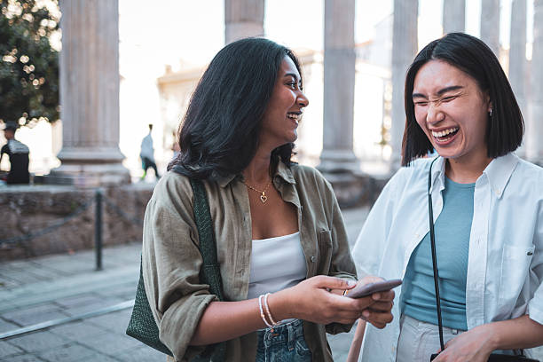 istock Two young women laughing together while using a smartphone in milan 2222911210