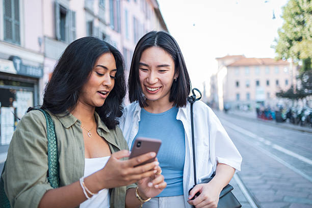 istock Two young women using a smartphone while walking in milan, italy 2222911261