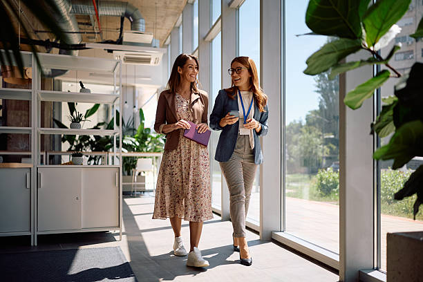 istock Happy female colleagues talking while walking through the office. 2222914080