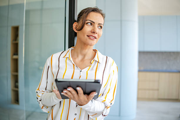 istock Confident woman in striped shirt using tablet in modern office setting during daylight hours 2222914400