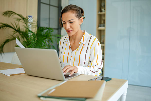 istock Focused woman working on laptop in a bright home office with plants and organized workspace 2222915564