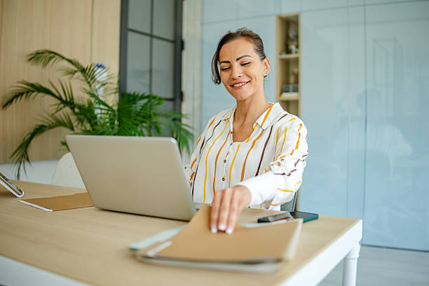 istock Professional woman working on her laptop in a modern office setting surrounded by plants and natural light 2222916604