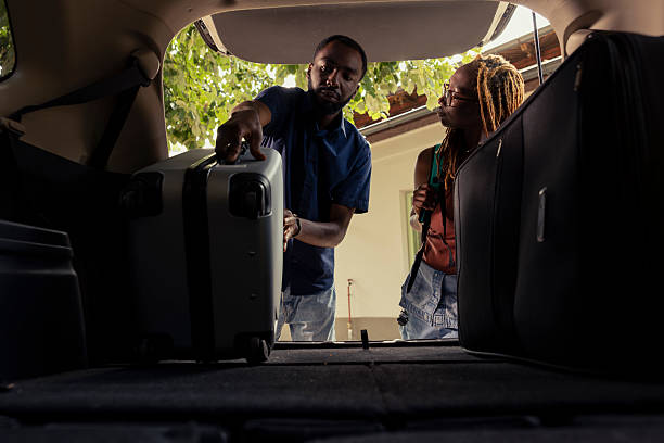 istock Black happy couple standing by their packed car and loading the trunk 2222917859