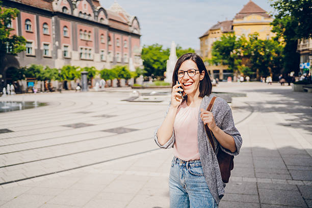 Young woman using phone and looking around the city. Concept of traveling.