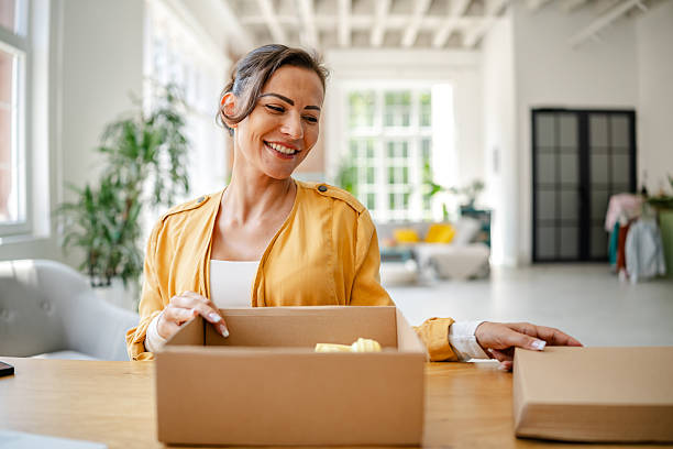 istock Woman smiling while unpacking cardboard boxes in a bright, modern workspace during daytime 2222919933