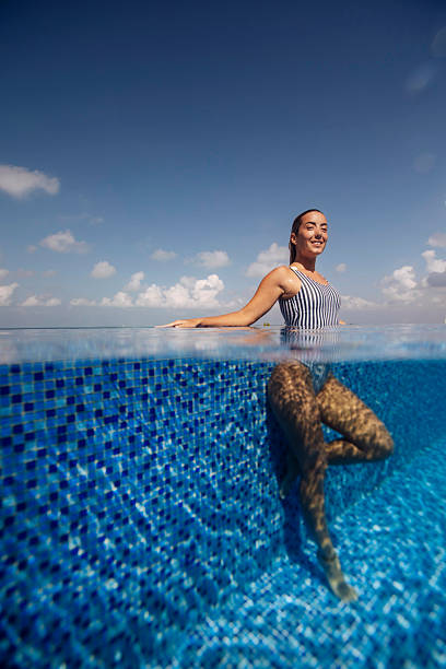 Beautiful woman is climbing ladders on a sailboat, getting out of the sea. The sea is beautiful turquoise color.