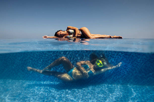 A serene scene of two women enjoying an infinity pool, one sunbathing on the edge while another swims underwater