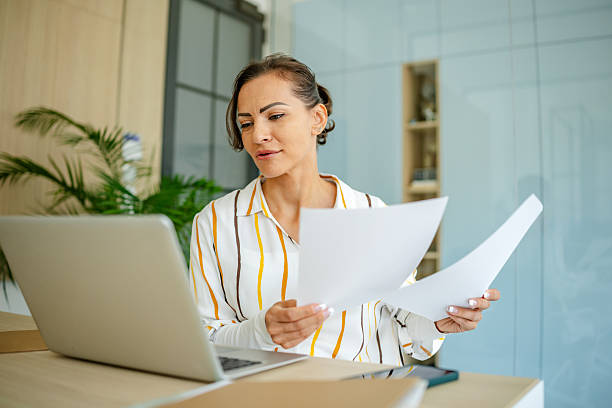 istock Woman working at home office reviewing documents on laptop in cozy interior setting during daytime 2222922325