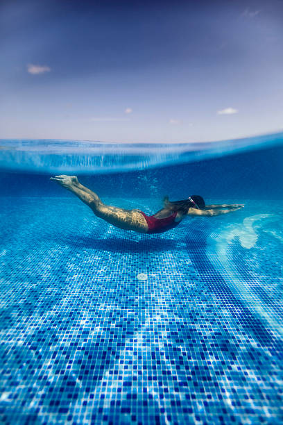 Child enjoying a refreshing swim underwater in a turquoise blue pool during summer vacation