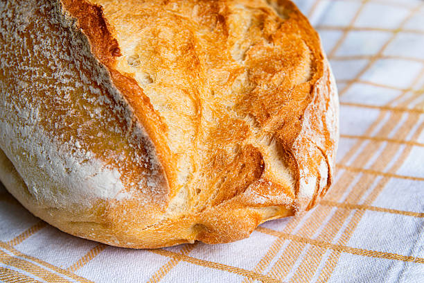 Freshly baked artisan bread resting on a cloth in a cozy kitchen setting during the afternoon