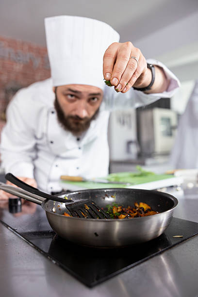 istock Professional chef in a modern kitchen carefully sprinkles fresh herbs 2222925882