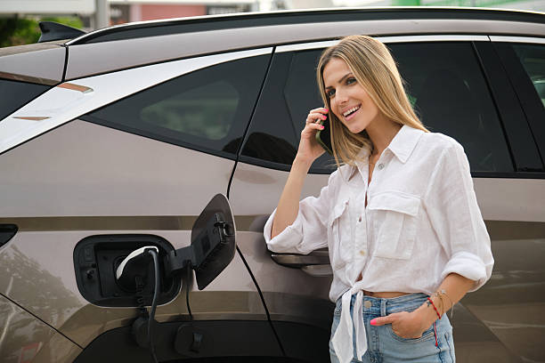 istock Young woman charging electric car and using smartphone 2222933920