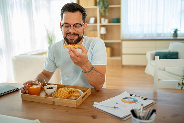 istock Young man enjoying waffles and orange juice for breakfast while working from home 2222937879