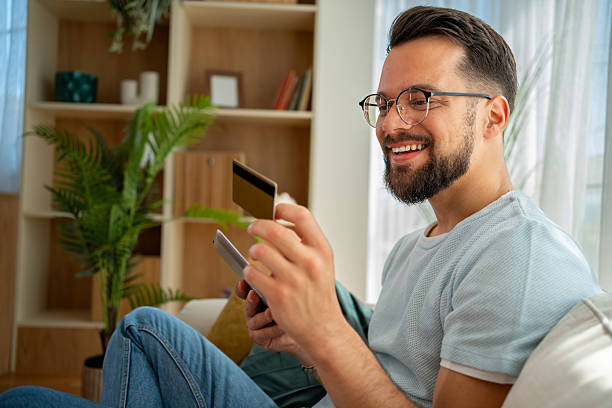 istock Smiling young man making online payment using credit card and smartphone 2222938270