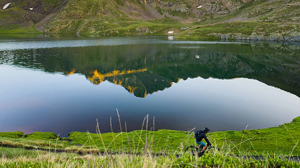 Cyclist enjoying the sunrise reflection on a pyrenees mountain lake.