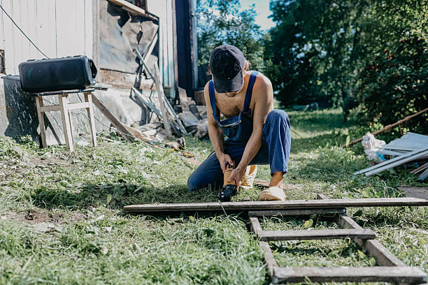 male builder restores old wooden house, replacing boards