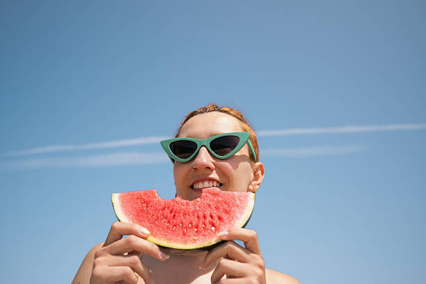 istock Young woman eating watermelon slice on the beach 2222948877