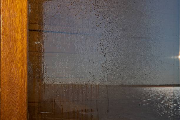istock Raindrops and condensation on window with blurred river landscape and sunlight. Abstract nature background 2222949943