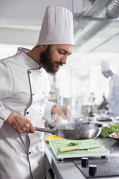 istock Dedicated chef in uniform cooking his dish perfectly at the kitchen stovetop 2222950922