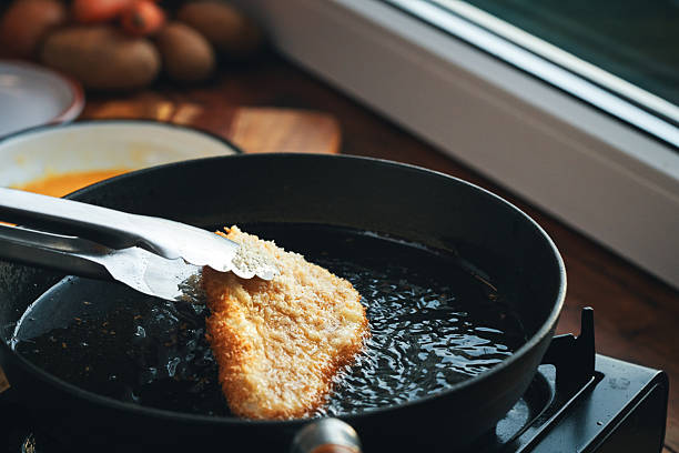 Roast crucian carp. A close-up of an appetizing piece of fish fried until golden crisp in breadcrumbs in a frying pan. A traditional homemade dish made with aromatic spices and oil.