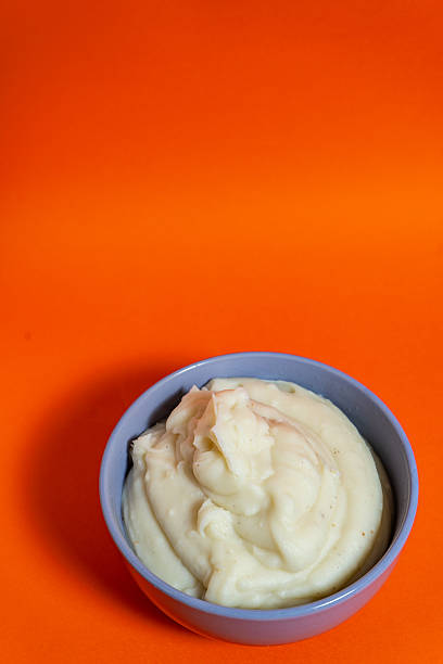 Creamy mashed potatoes served in a blue bowl on vibrant orange background