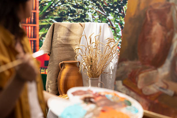 Woman painter admires her masterpiece drying on canvas in art studio, creating a rustic artwork filled with emotion and color. Artistic process highlights her talent and inspiration.