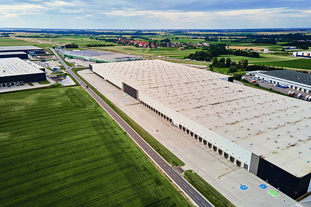 istock Large modern warehouse with loading docks in green rural landscape 2222958168