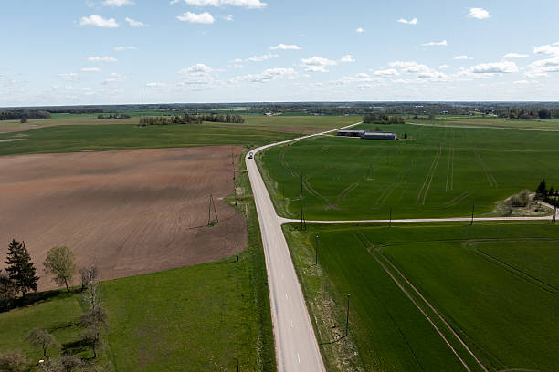 istock Rural Fields with Paved Road and Utility Poles Under Cloudy Sky 2222960316