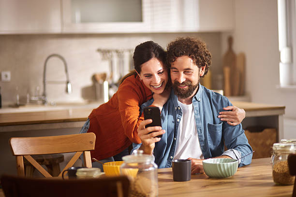 istock Happy couple sharing a moment while having breakfast and using smartphone at home 2222962576