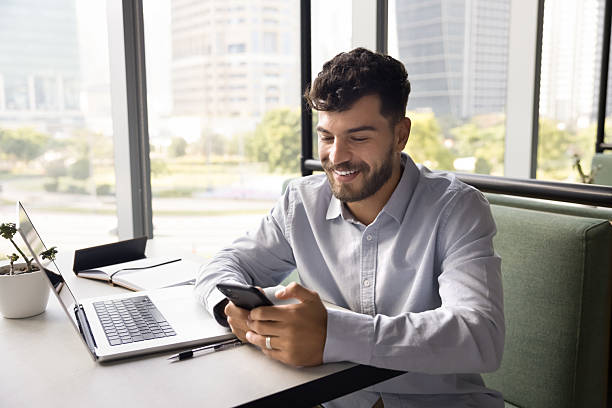 istock Smiling student sitting at table by notebook texting on phone 2222963145