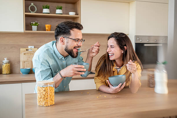 istock Happy couple feeding each other while having breakfast in the kitchen 2222963386
