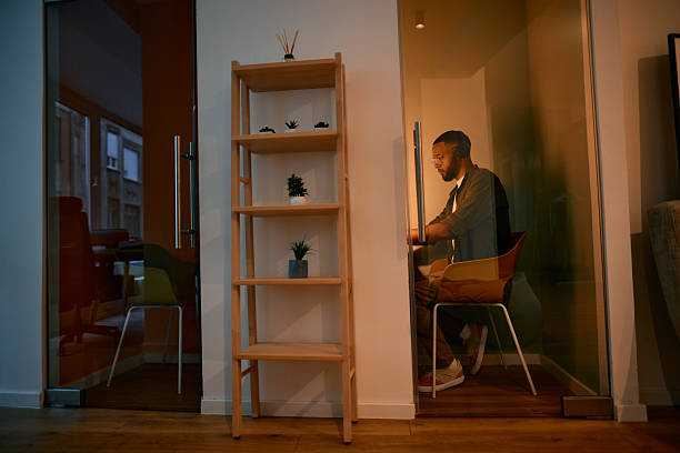 Young adult male employee is concentrating on his work in a private office cubicle, highlighting the modern workspace and dedicated work ethic